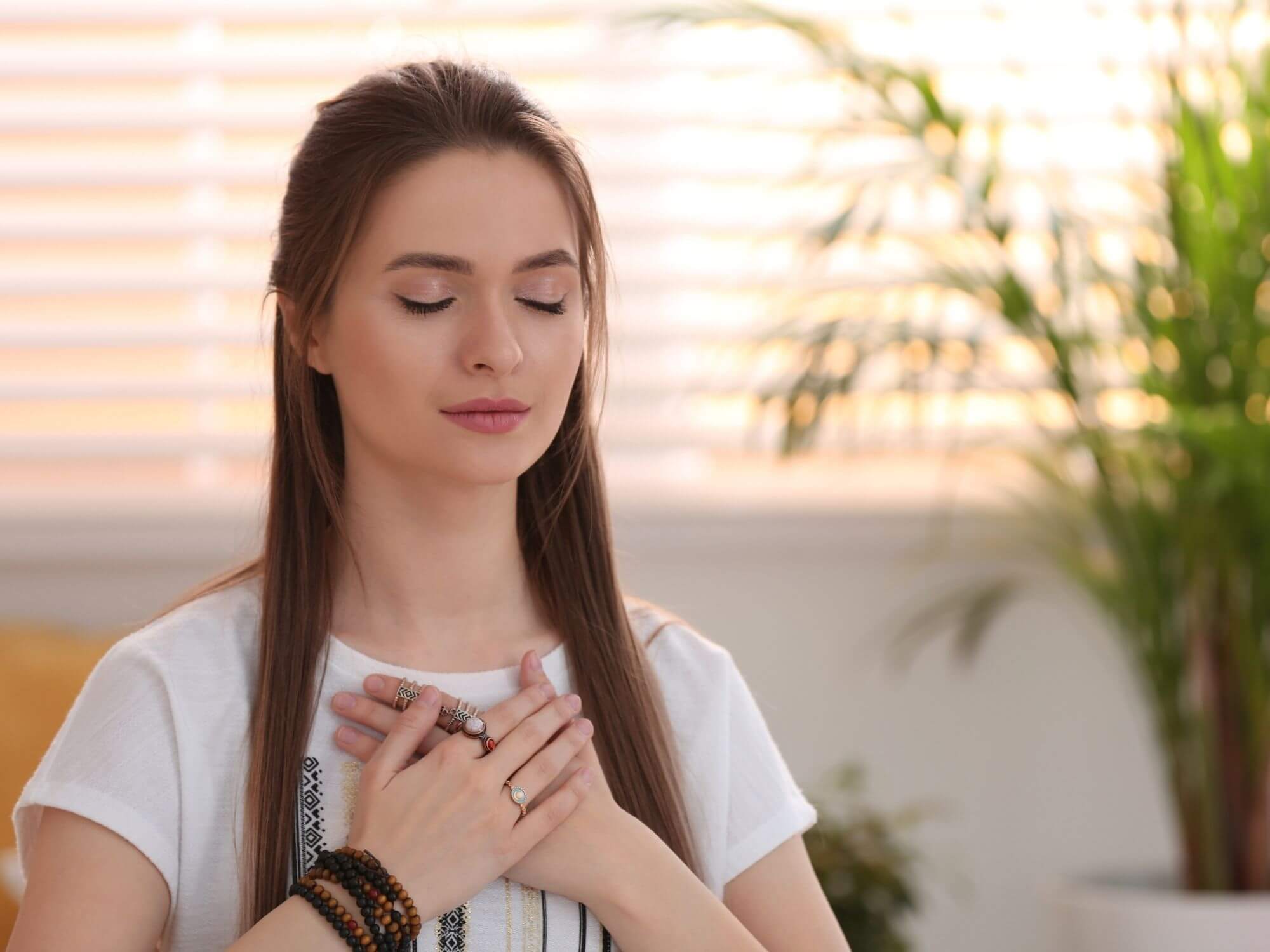 A woman at a sober living home holding her hands over her chest with her eyes closed