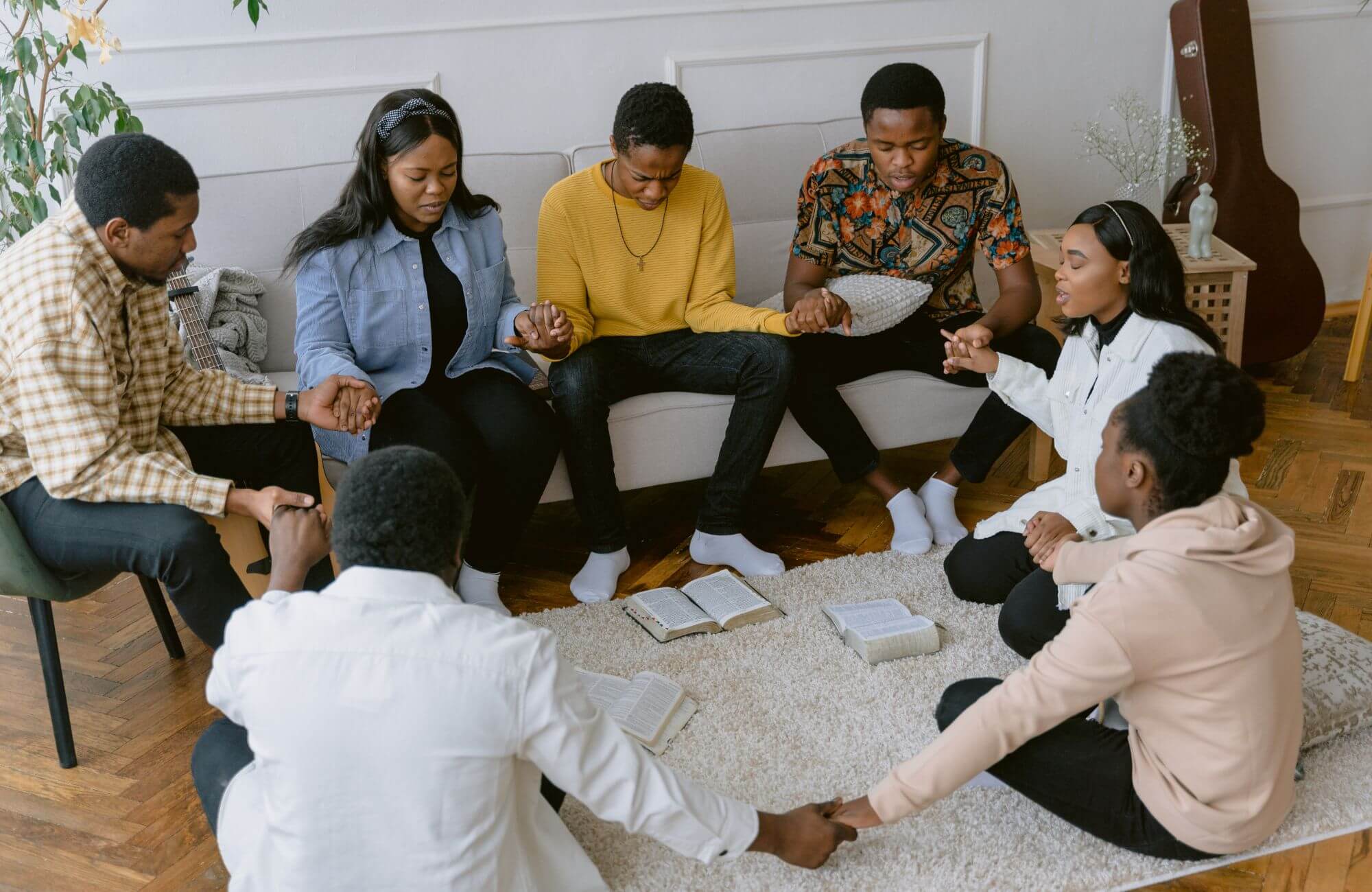 A group of people holding a prayer meeting in a sober living home